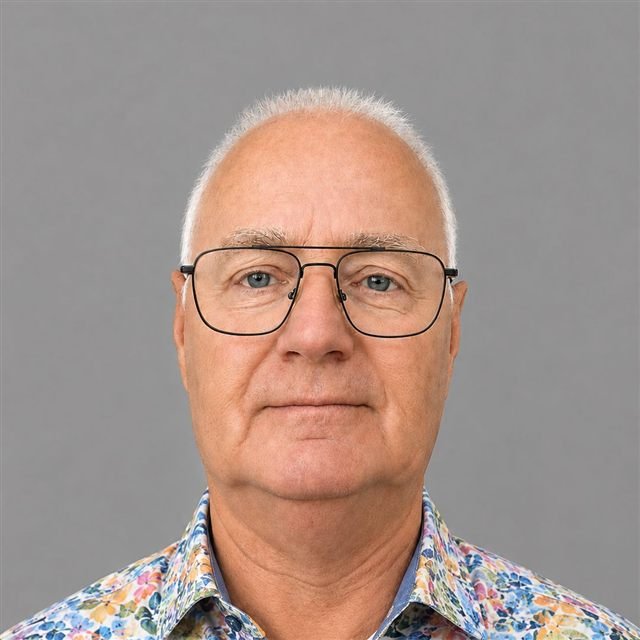 Porträt von Rüdiger Frenzel, lächelnd vor grauem Hintergrund